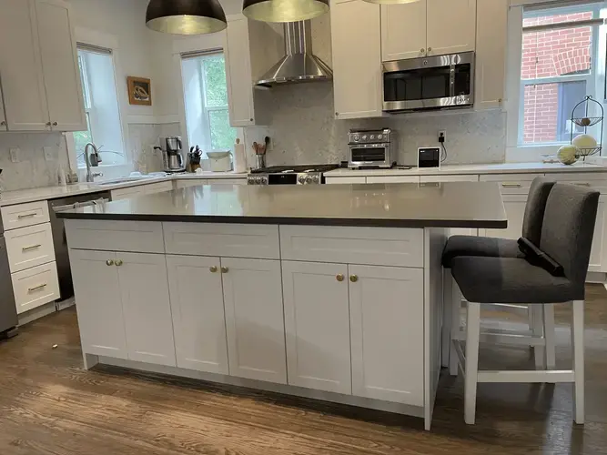 White shaker-style kitchen with island seating and stainless steel appliances