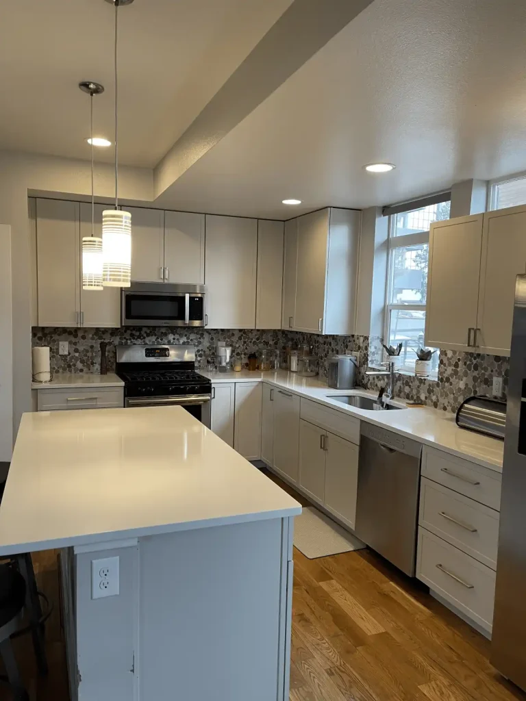 Custom kitchen design in Aurora with white cabinets, quartz countertops, and stylish pendant lighting