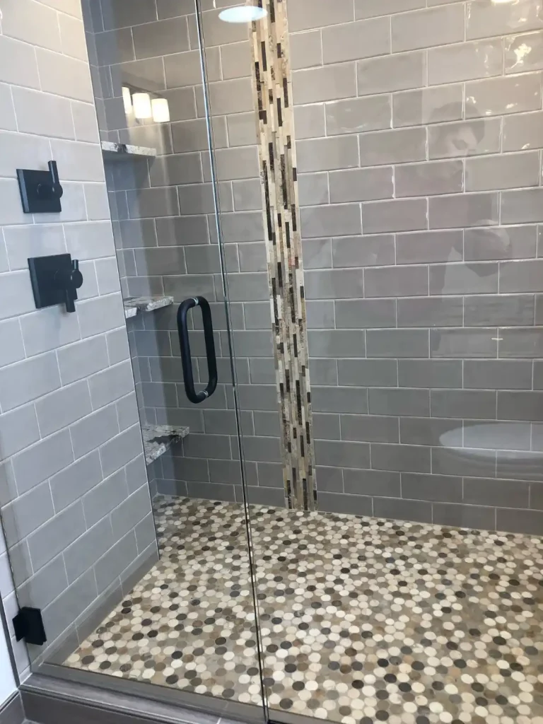 Stylish bathroom remodel featuring glass shower enclosure, sleek black fixtures, and built-in marble corner shelves