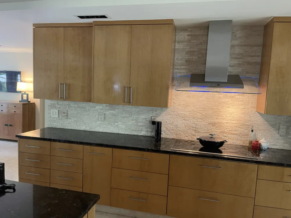 Modern kitchen remodel with natural wood cabinets and black granite countertops